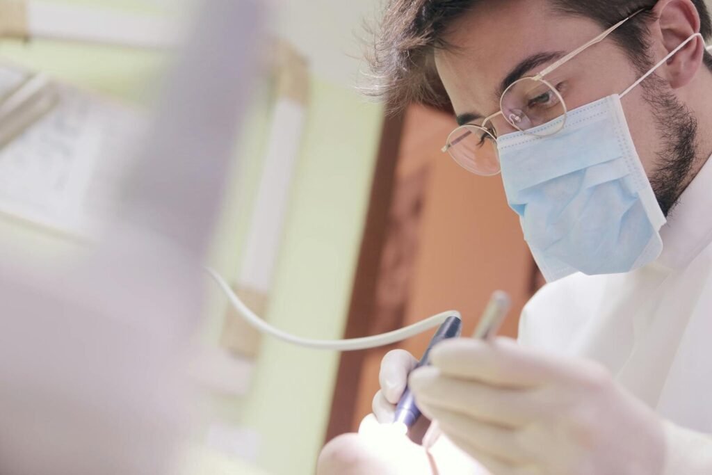 Medical professional wearing mask and gloves working with equipment indoors.